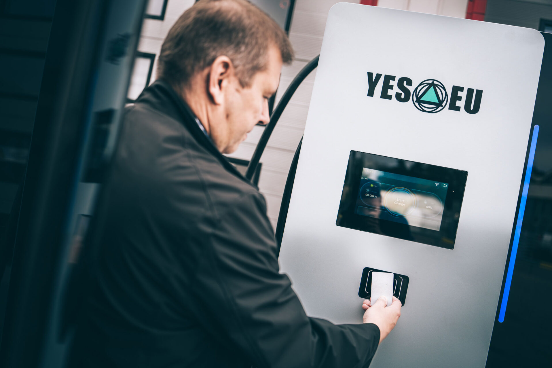 Mies käyttää YES-EU:n latauslaitteen maksupäätettä