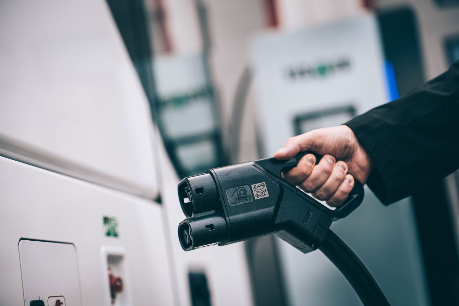 Käsi pitelee CCS-latauspistoolia YES-EU:n latausasemalla